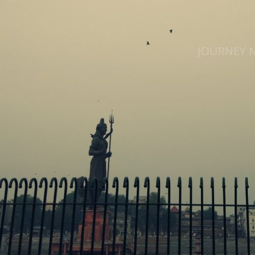 Scenic lake in Vadodara featuring a Shiva statue surrounded by urban landscapes